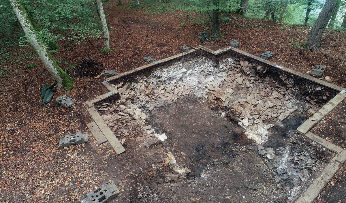 Althayingen. Zwischen zwei Mauerköpfen und mit hellem Material verfüllten Pfostengruben verläuft die etwa 3 m breite Torgasse. Verkohlte Hölzer und weißlich zersetzte Steine sprechen für einen großen Brand.