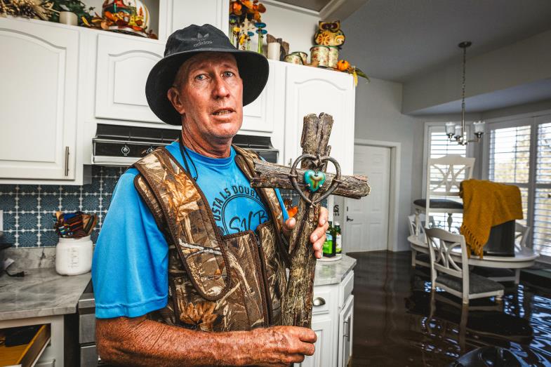 Ein Mann mit Kreuz in der Hand steht in seinem von Hurrikan Milton zerstörten Haus