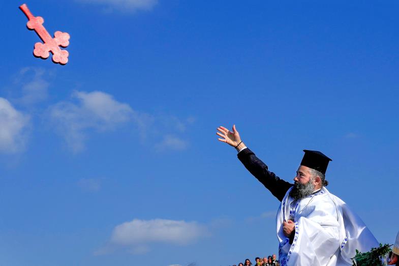 Orthodoxer Priester wirft als Zeichen des Segens Holzkreuz ins Meer