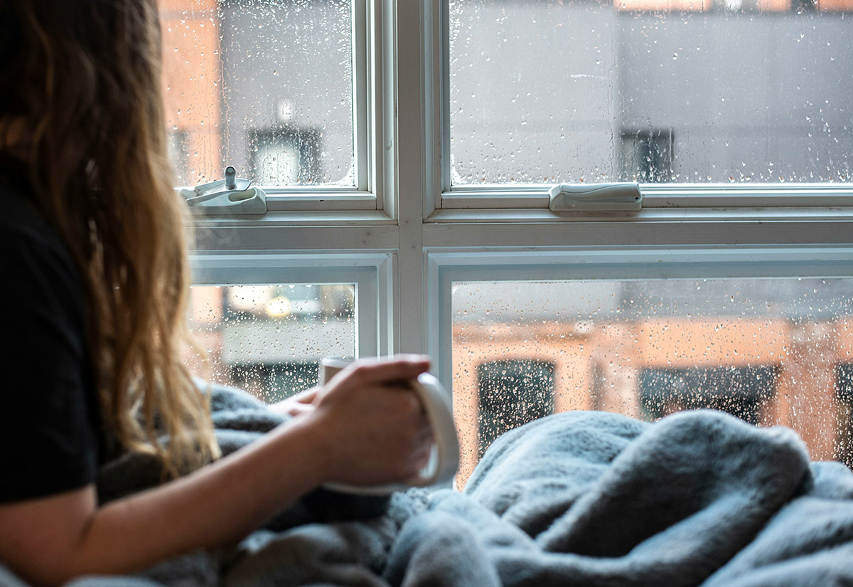 Frau mit einer Tasse Kaffee schaut aus dem Fenster