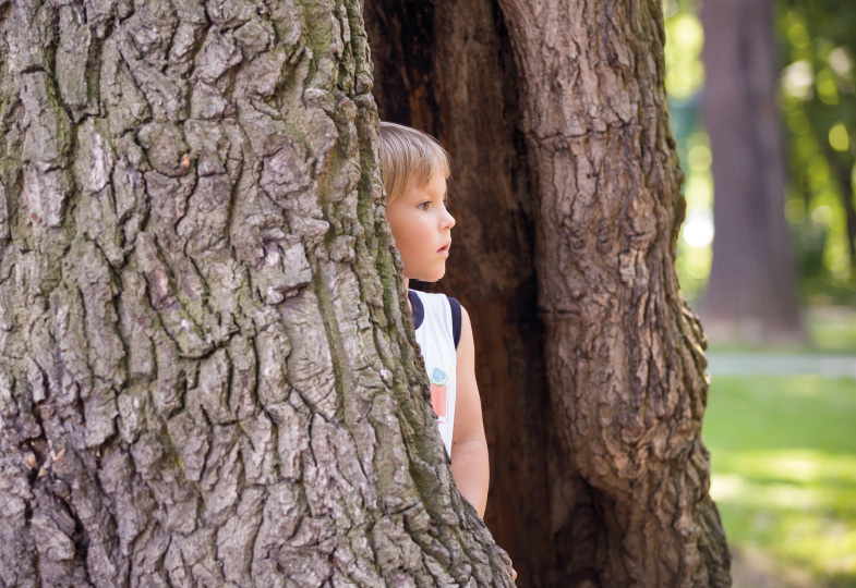 Kind lehnt sich an Baum