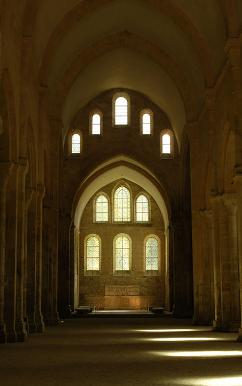 Das Innere einer Kirche oder Abtei mit hohen gewölbten Decken und massiven Steinsäulen.