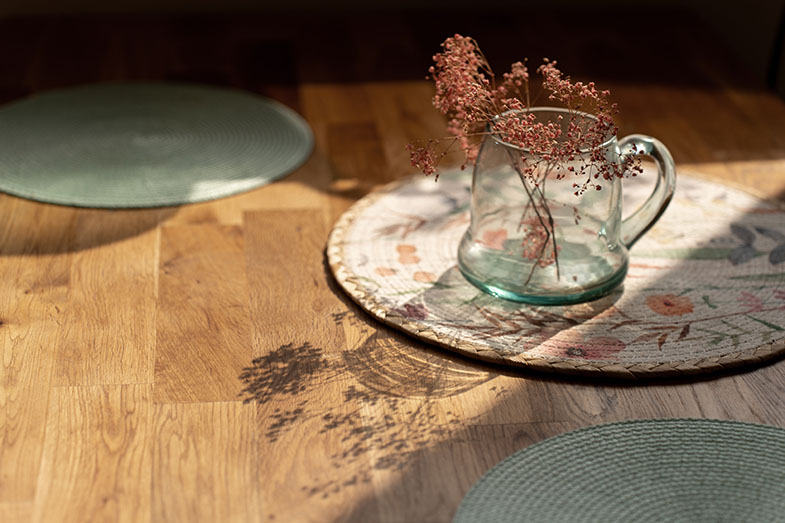 Blumen in einer Vase auf einem Holztisch, in einem modern aussehenden Wohnzimmer mit sanftem Licht