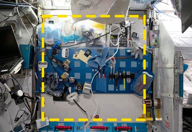 Ein Probenort aus dem Sampling Quadrangle Assemblages Research Experiment (SQuARE), Quadrat 03 im Steuerbord-Wartungsarbeitsbereich der Internationalen Raumstation. Rechts ist eine offene Mannschaftskoje zu sehen. Die gelbe gepunktete Linie zeigt die Grenzen des Probenahmebereichs an.