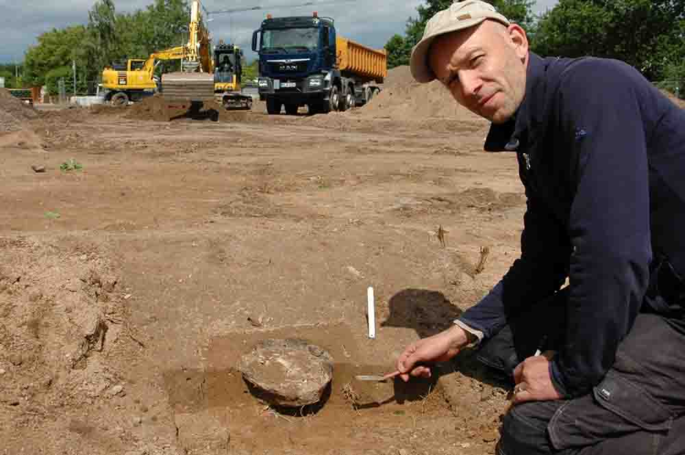 Beschädigt, aber dennoch ein wichtiger Fund: Die Reste dieses Urnengrabs in Petershagen-Lahde werden von Christoph Storz von der Fachfirma Archäologie am Hellweg eG freigelegt.