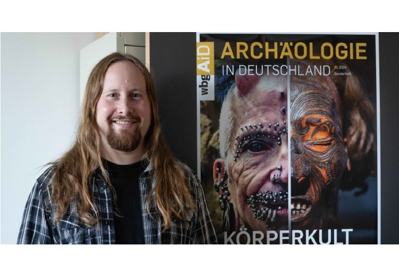 Lukas Kerk gibt das Sonderheft „Körperkult“ der Zeitschrift „Archäologie in Deutschland“ heraus. Rolf Buchholz auf der linken Posterhälfte im Hintergrund gehört zu den meistgepiercten Menschen der Welt, rechts auf dem Bild ist ein mumifizierter und tätowierter Kopf eines Angehörigen des Stammes der Maori (Neuseeland) zu sehen.