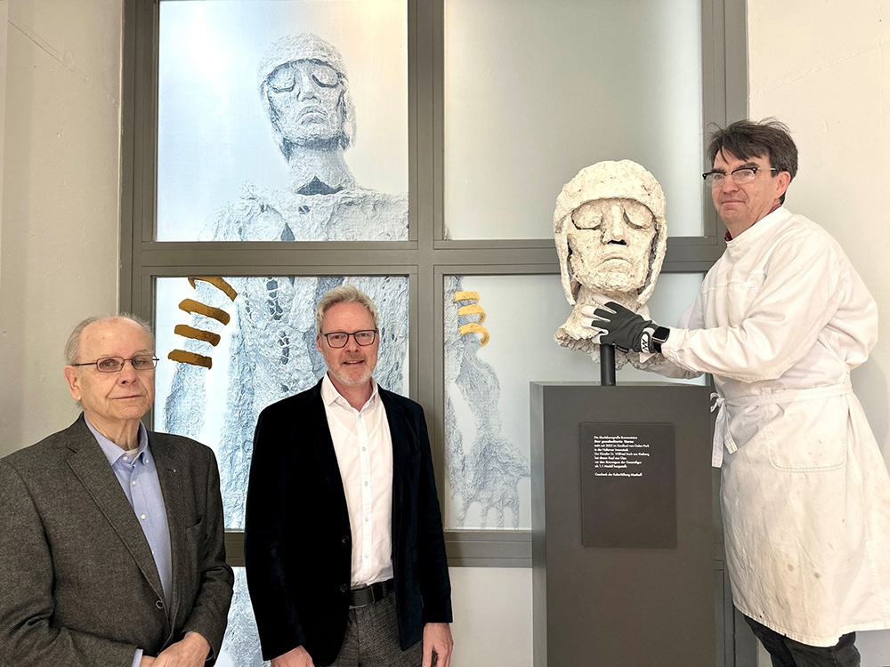 Dr. Horstfried Masthoff von der KulturStiftung Masthoff und Dr. Josef Mühlenbrock, Leiter des LWL-Römermuseums, wohnen der Aufstellung des neuen Exponats des Haupts des Varus durch den Restaurator der LWL-Archäologie für Westfalen, Andreas Weisgerber (v.l.), bei.